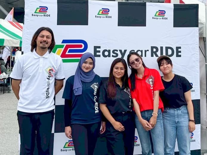 Staff standing in front of Easy car RIDE flag
