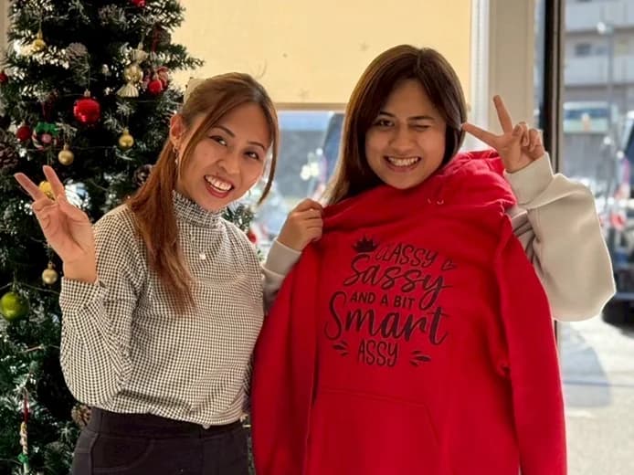 Female staff showing peace sign in front of a Christmas tree